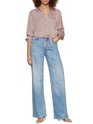a silky long sleeve v neck collared blouse with a pink petal grid and a tie at the hem worn with light blue jeans