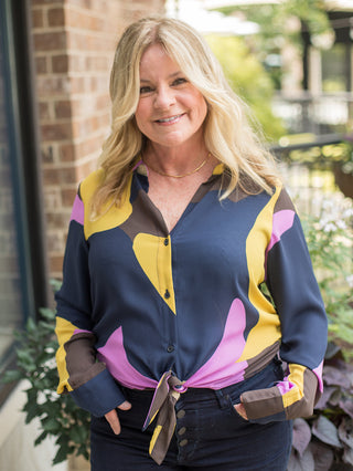 a multicolor blouse in jewel tones with a tie at the waist and long sleeves perfect for transitional dressing