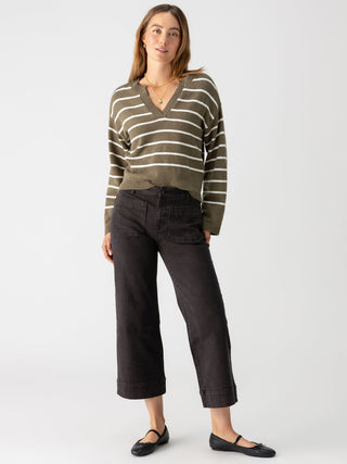 a pair of black cropped wide leg denim jeans worn with a green striped sweater