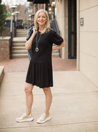 relaxed half sleeve above the knee black dress with elastic bubble sleeve detail worn with gold tennis shoes