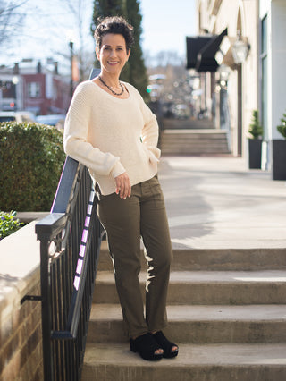 a pair of olive green pants with utility pockets shown with ribbed cream sweater