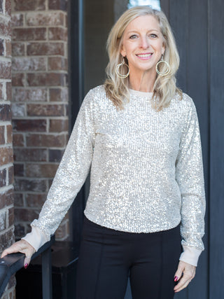 an off white sequin and glitter long sleeve top with a relaxed fit perfect for holiday season fashion and glamorous dressing