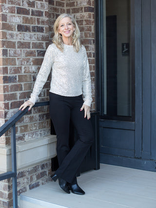 an off white sequin and glitter long sleeve top with a relaxed fit perfect for holiday season fashion shown with black pants