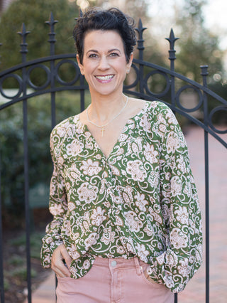 a green and pale pink floral blouse with a v neckline and relaxed long sleeves