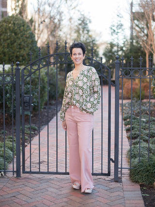a green and pale pink floral blouse with a v neckline and relaxed long sleeves shown with pink pants