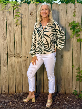 a breezy green and white tropical print blouse with a button up front worn with white pants