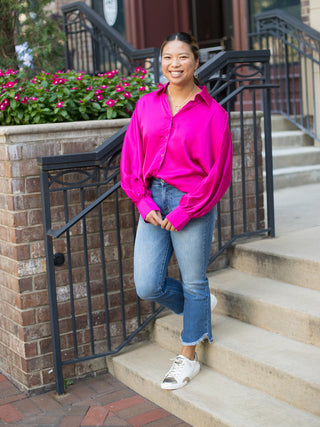 a hot pink satin blouse in a relaxed fit with dramatic sleeves shown with cropped denim pants