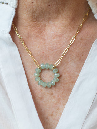 a statement necklace featuring sea foam aqua green crystal beads in a circle along a gold paperclip chain