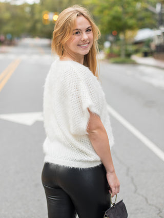 an ivory fuzzy top with drop short sleeves and an oversized fit with alluring open knit shown with faux leather leggings
