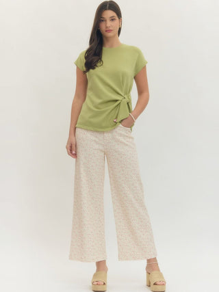 a matcha green crewneck blouse with a fun side tie paired with cream pants