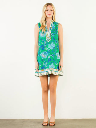 a vibrant tropical sleeveless mini dress with a green and blue floral pattern worn with brown sandals
