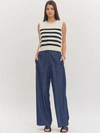 a soft cream and black striped sleeveless sweater top with gold buttons worn with blue pants