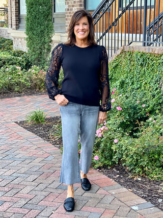 a black crew neck sweater with long lace crochet sleeves great for everyday fall and winter fashion shown with black loafers