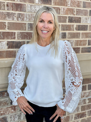 a white crew neck sweater with long lace crochet sleeves great for everyday fall and winter fashion