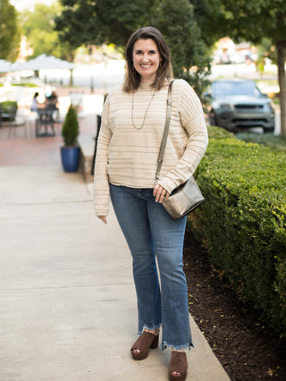 an off white mock neck sweater with long sleeves and subtle stripes perfect for summer to fall fashion shown with denim