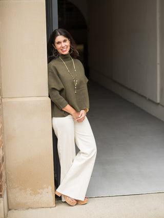 a loose crop turtleneck in a hunter green sweater material perfect for thanksgiving day outfits with ivory wide leg pants