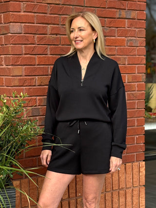 Person wearing black spanx shorts with a tie paired with a black jacket