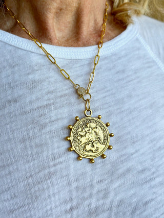 a matte gold paperclip necklace with a dotted st george medallion charm