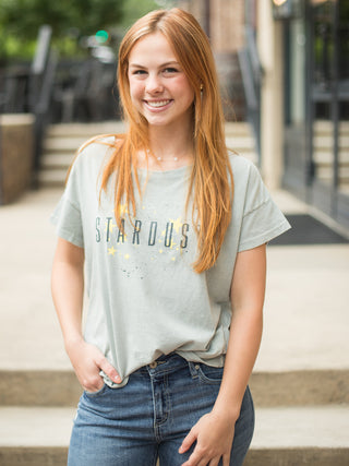 a short sleeve cotton top in pale blue that reads stardust with yellow stars accenting the vintage letters