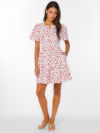 a charming white mini dress with strawberry fields and a cinched waist worn with white sandals
