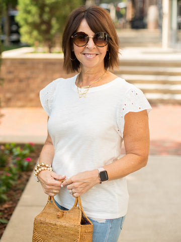 a white cotton top with floral eyelet cap sleeves