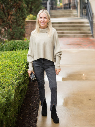 a beige ribbed turtleneck sweater with long statement sleeves perfect for fall fashion shown with black jeans