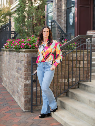 a button down blouse in bright jewel tone print with long statement sleeves perfect for fall fashion shown with denim pants