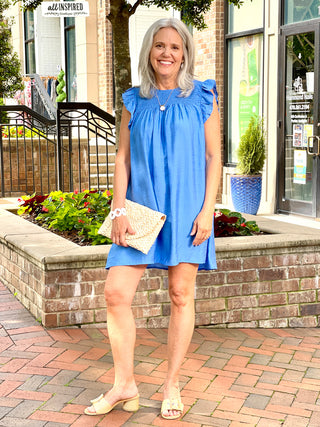 lightweight breezy blue mini dress with ruffled armholes and smocked yoke for flattering fit worn with natural sandals
