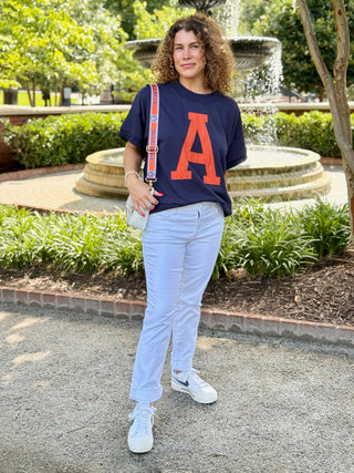 a short sleeve navy sweatshirt top with a burnt orange auburn a on the front worn with white jeans