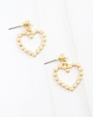 a pair of dangling gold heart shaped earrings with pearls