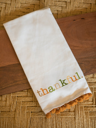 an ivory hand towel with burnet orange pom pots along the edge that reads thankful perfect for thanksgiving decor and gifts