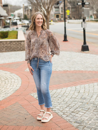 a flowy long sleeve leopard print button front top with tie worn with denim jeans