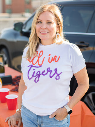 a white sweater tshirt with orange and purple glitter text that reads all in tigers perfect for clemson football fans