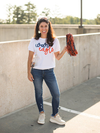 a white sweater tshirt with blue and orange glitter text that reads war eagle made for auburn fans shown with tiger earrings