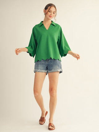 a relaxed green scalloped top with a v neck collar and half sleeves worn with denim shorts