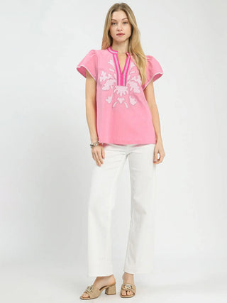 a spring pink abstract v neck top with a textured pattern worn with white pants