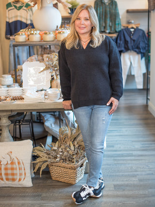 a v neck black sweater with long cuffed sleeves and a relaxed fit perfect for fall and winter fashion shown with denim pants