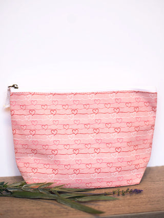 a pink cosmetics bag with red and white heart patterns