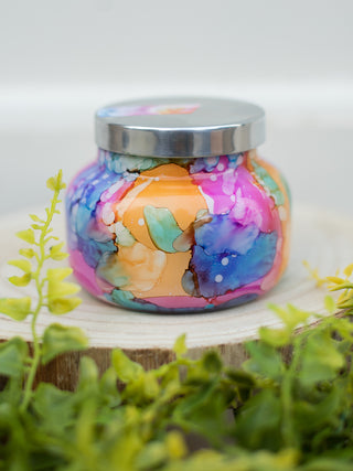 a tropical scented candle in a rainbow watercolor mini jar