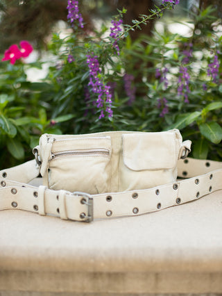 an ivory leather sling bag with a studded shoulder strap and casual silhouette great for fall fashion