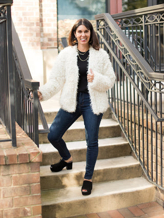 an ivory fuzzy jacket with long sleeves and an open front perfect for easy layering in fall and winter shown with denim