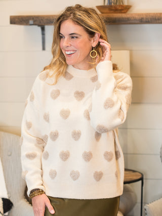 an oversized beige sweater with raised tan hearts perfect for fall and winter fashion especially valentines day dressing