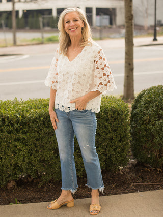 white half sleeve lace design top with delicate floral appliqués worn with denim jeans