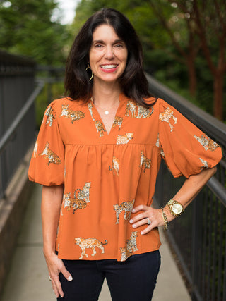 an orange short sleeve blouse with cheetahs printed across the silhouette with statement sleeves great for wild style