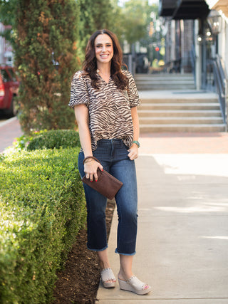 a zebra print top in brown and beige with short puff sleeves and a v neckline to bring animal print shown with dark denim