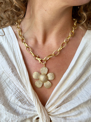a chunky gold oval link chain necklace with a large etched wildflower pendant