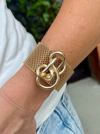 a gold mesh band bracelet with a center knot and a convenient magnetic closure 