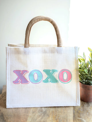 white jute gift tote that reads xoxo in multicolored font with handles for every gift giving occasion