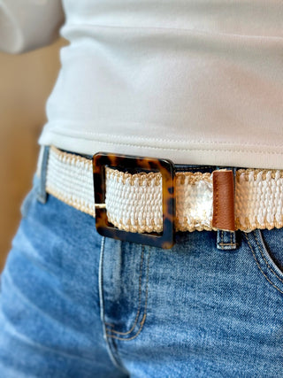 a white and tan stretchy woven belt with a plastic square buckle