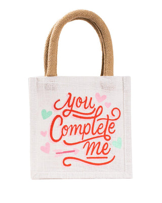 a white jute gift tote bag that says you complete me